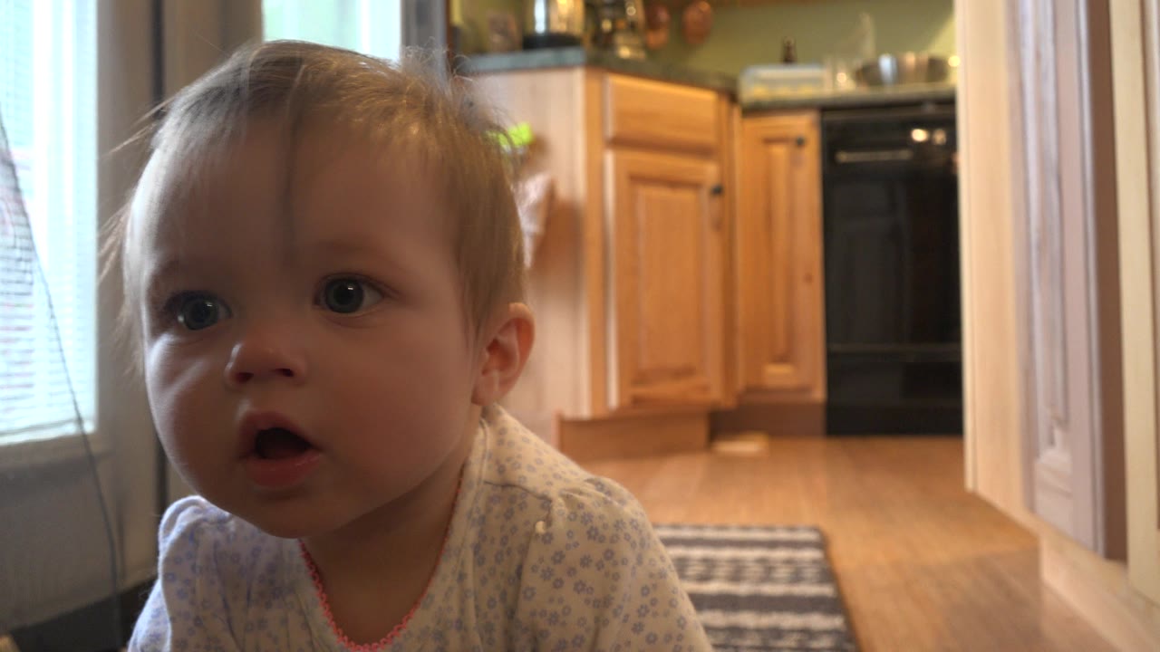 Toddler close to the camera near a kitchen doorway.