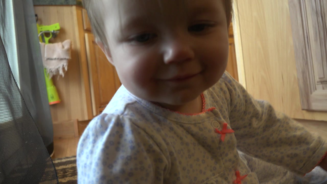 Blond baby close to camera in a kitchen highchair.