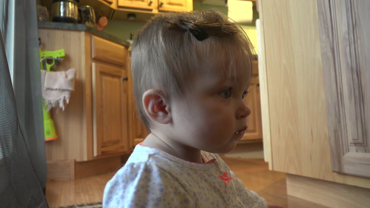 Baby girl in profile near a kitchen doorway.