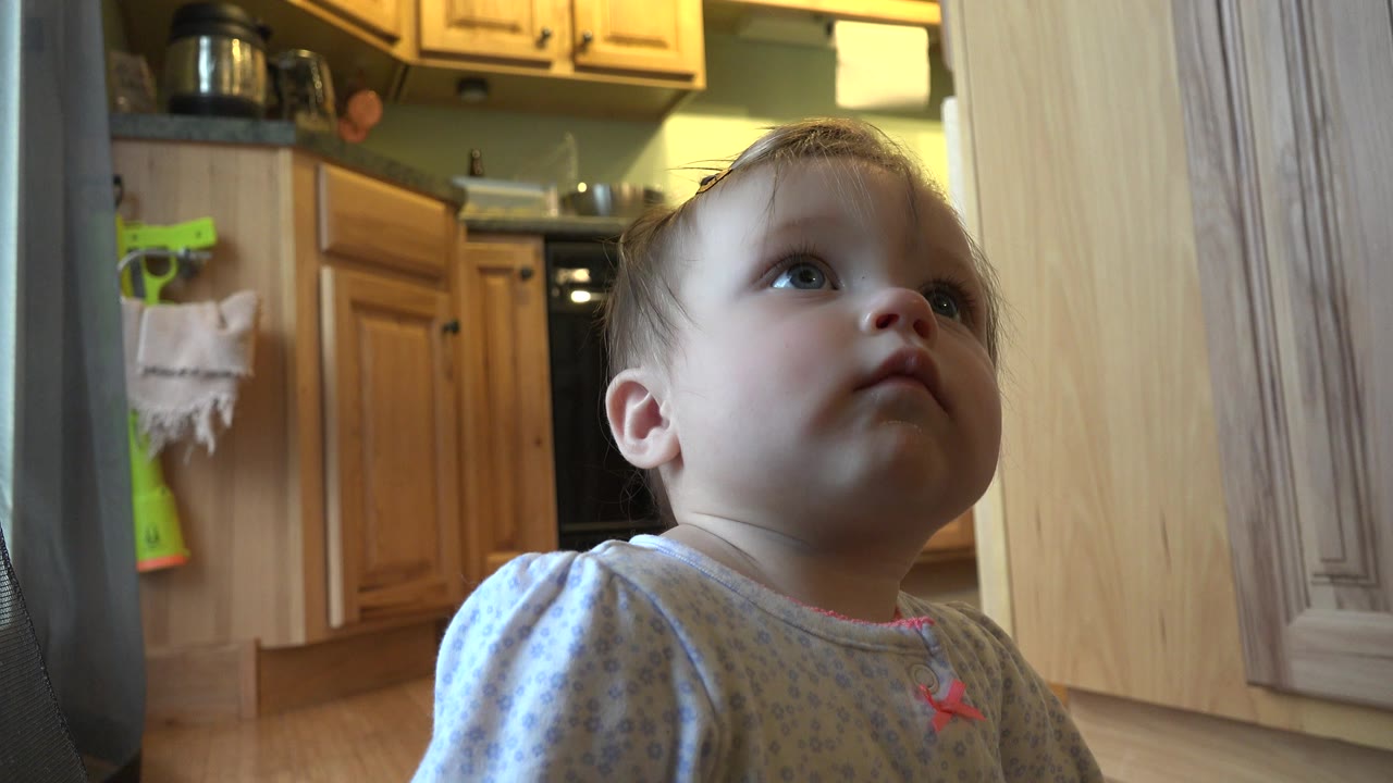 Baby looking upward in a home kitchen.