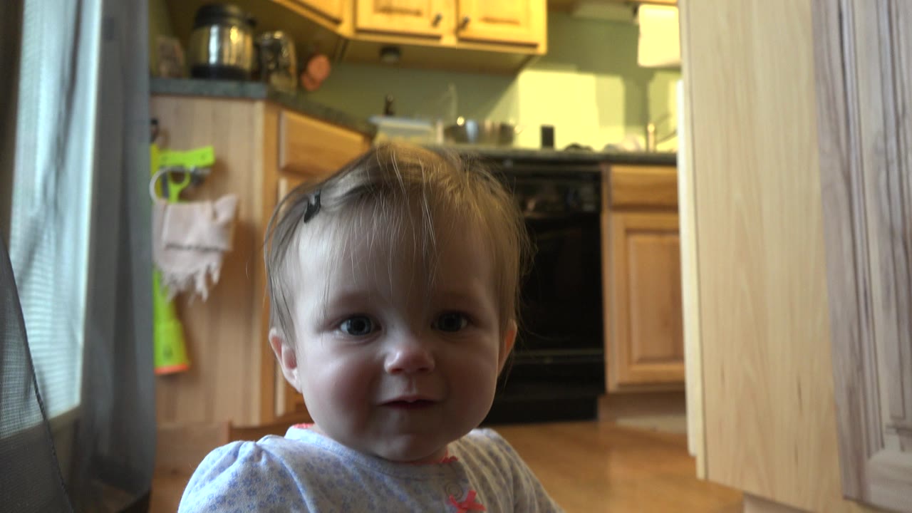 The baby faces the camera more directly in the Westminster, Colorado home kitchen, with a black oven and pale wood cabinets visible in the background.