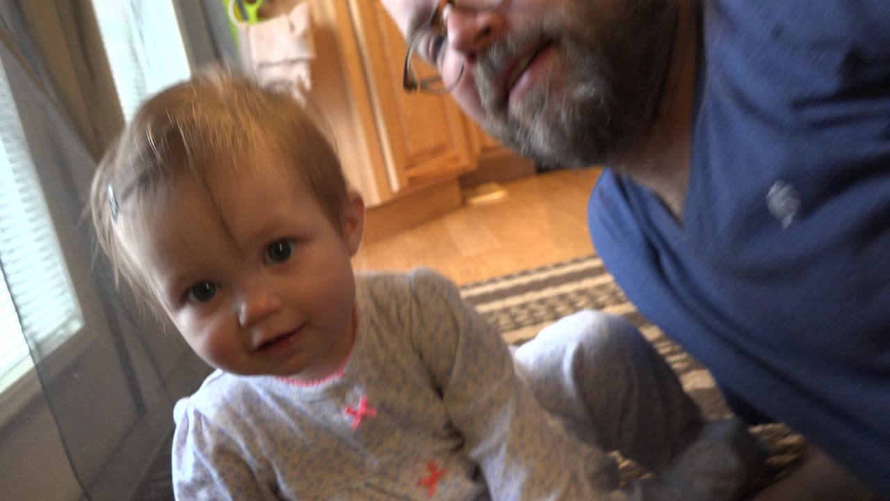 Infant near an adult on a floor by glass doors.