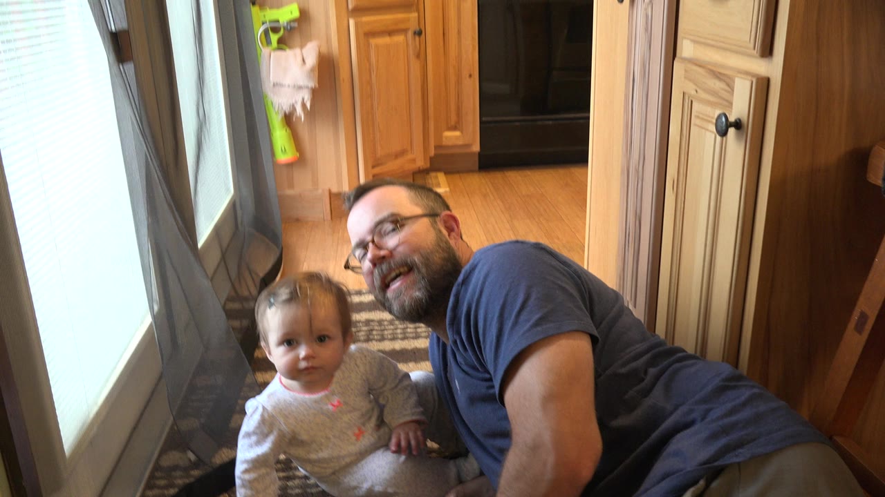 Toddler and father on a rug near a bright door.