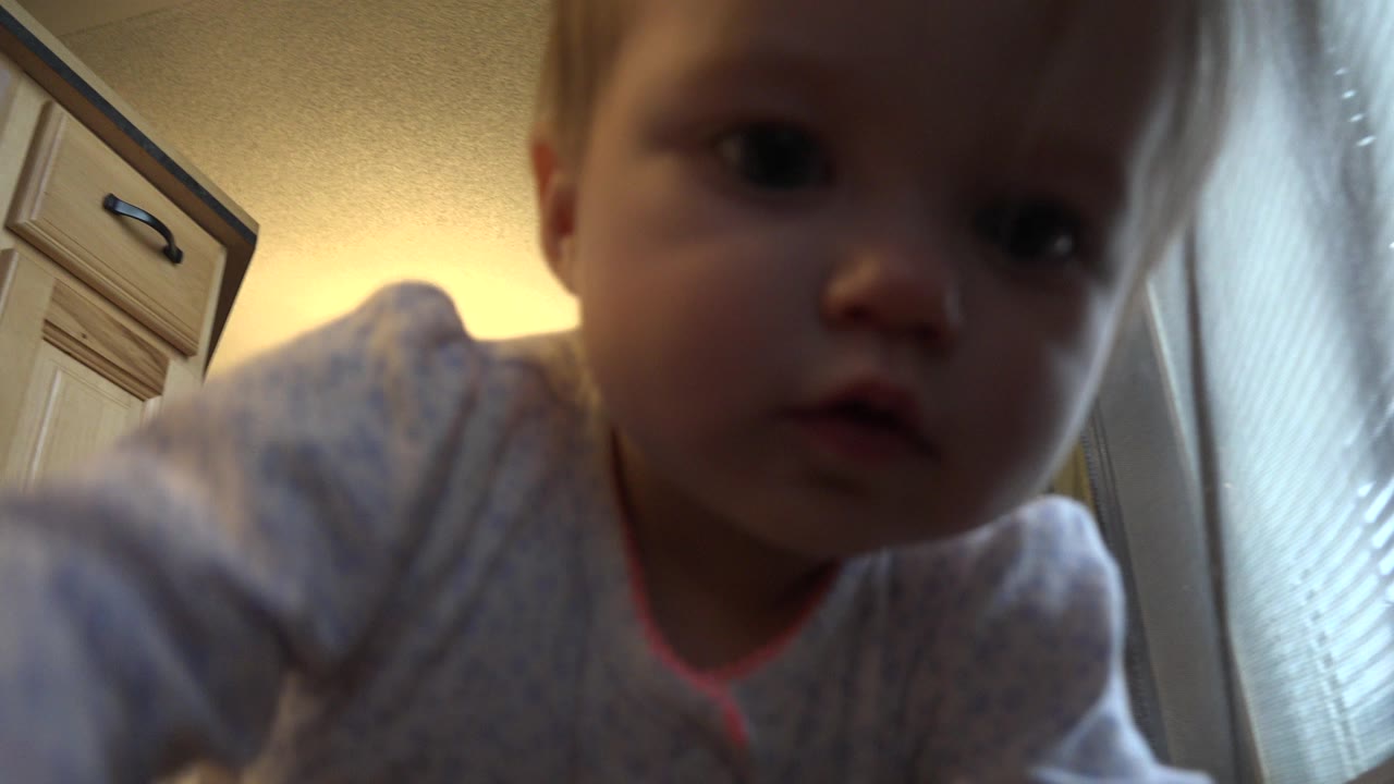 Baby close to a low camera inside a home.