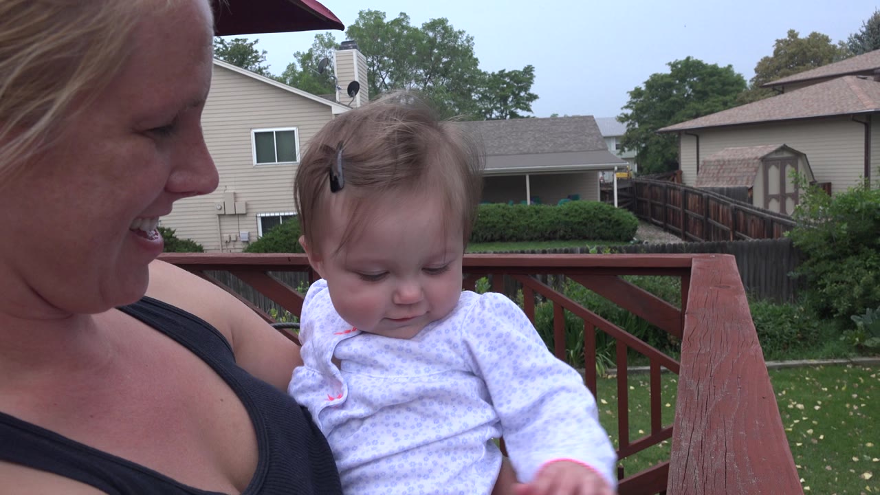 Mother holding baby on a backyard deck.