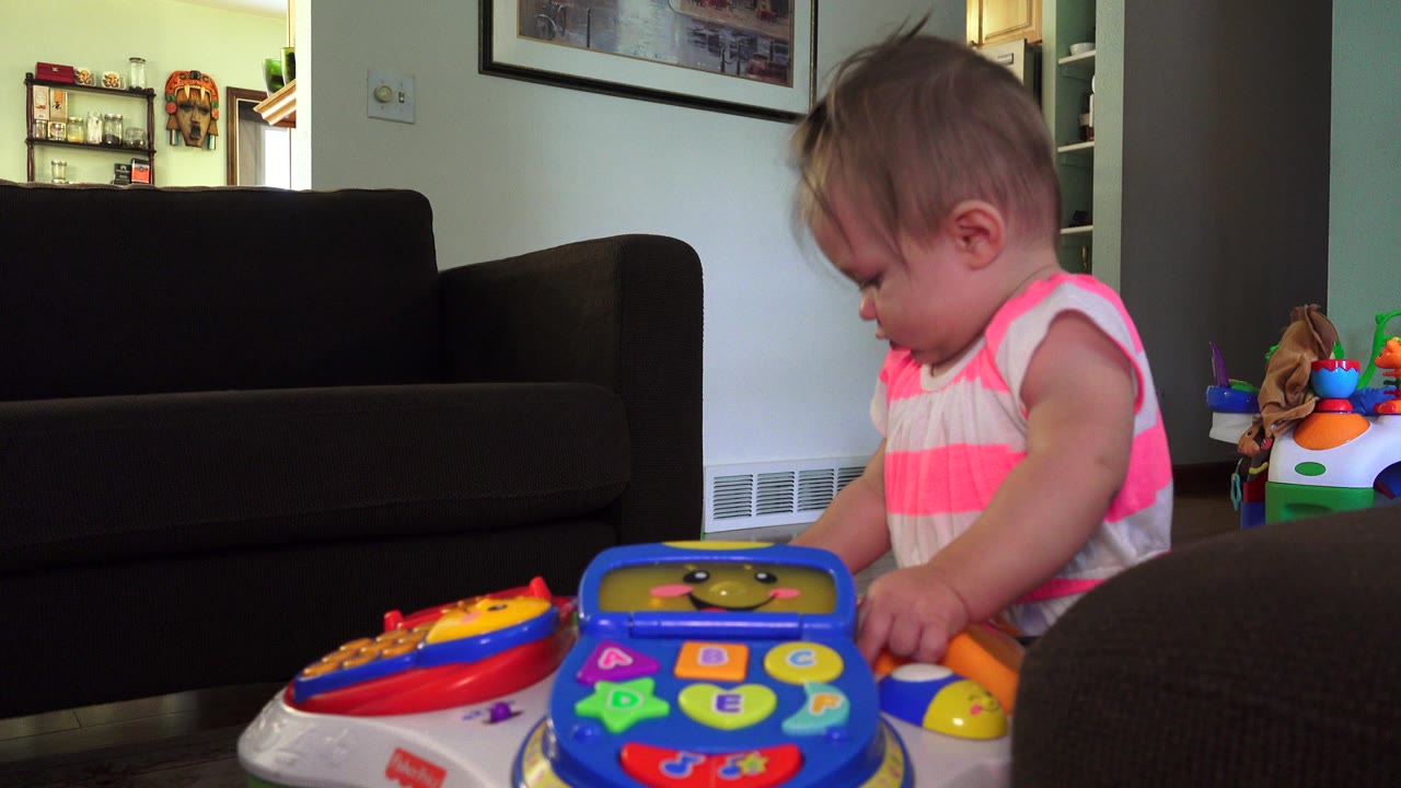 Toddler leans near a toy table in front of living room furniture.