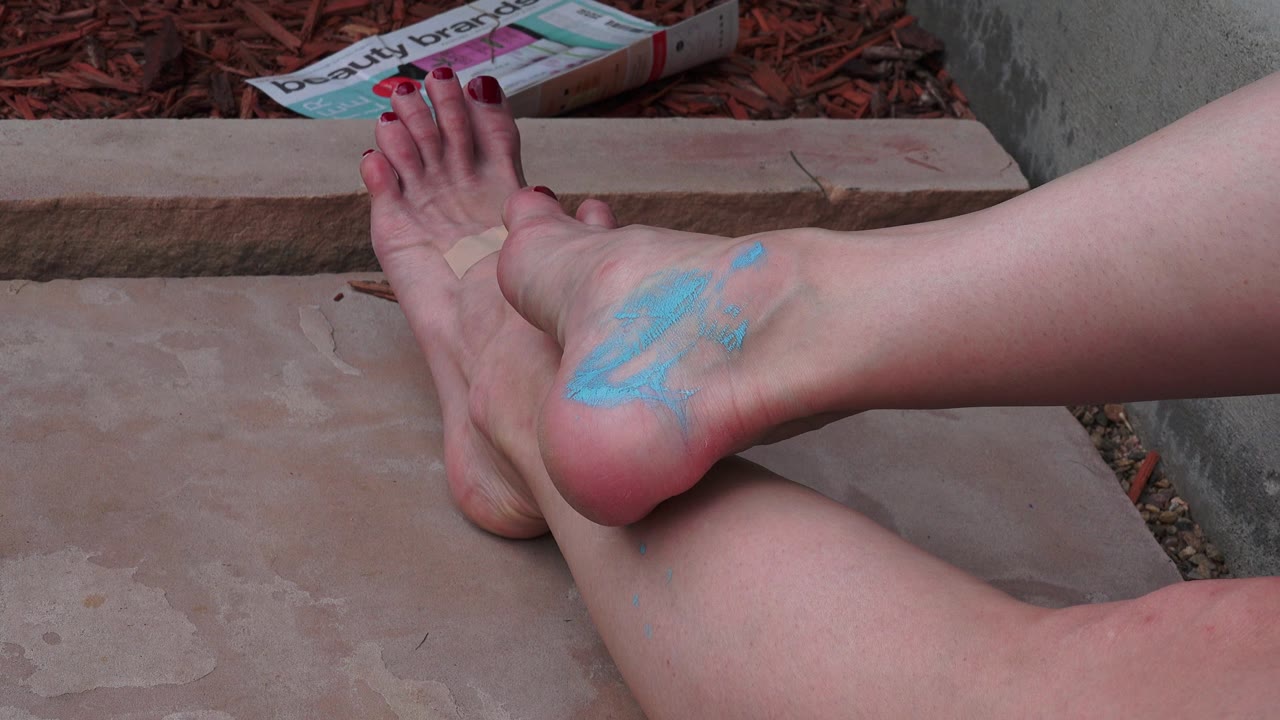 Bare foot lifted with blue paint on the heel.
