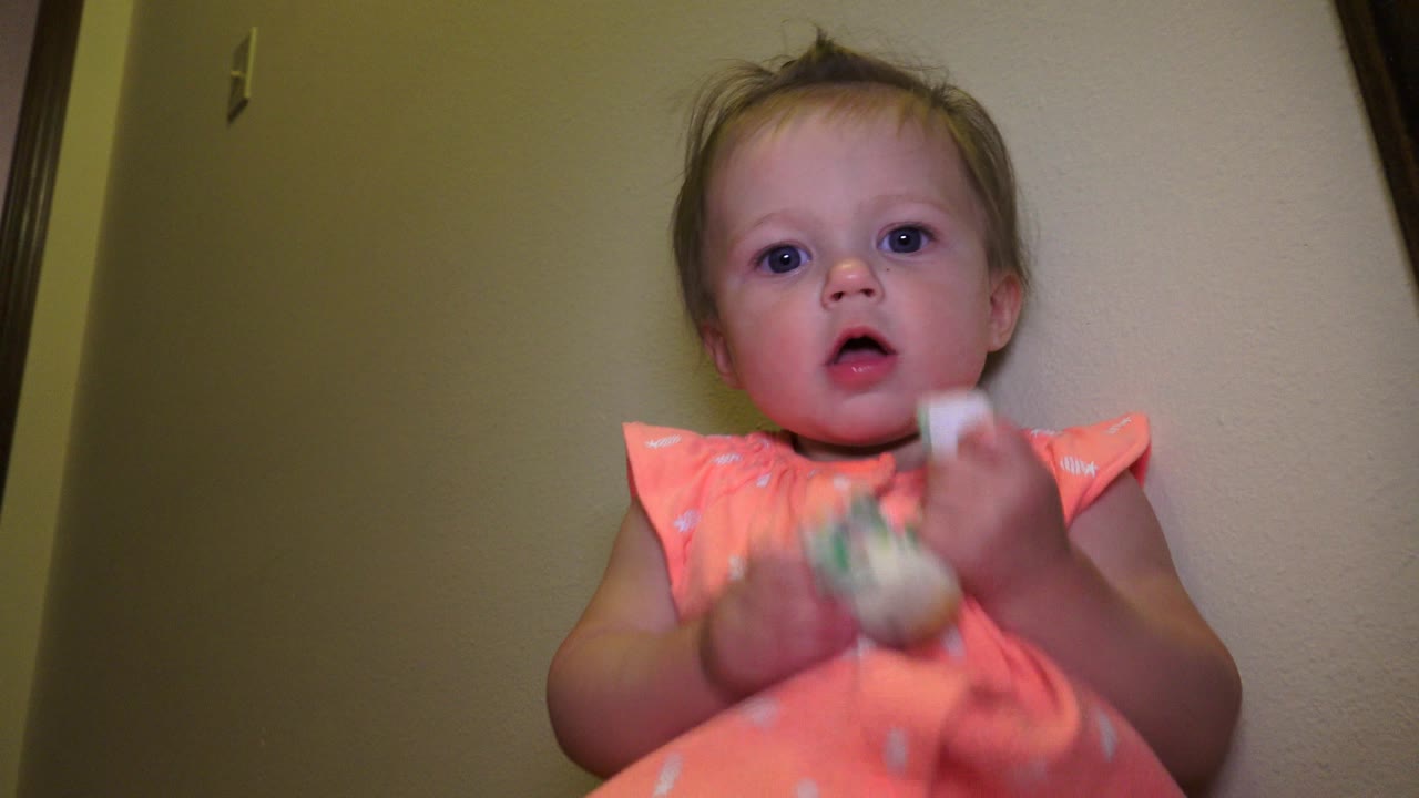 The young child remains seated in the Broomfield, Colorado home interior, facing the camera as the toy blurs slightly in her hands.