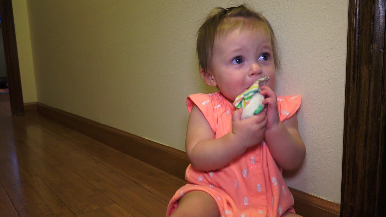 In Broomfield, Colorado, the seated baby grips the toy with both hands and looks slightly off camera beside beige walls and dark wood doorway trim.