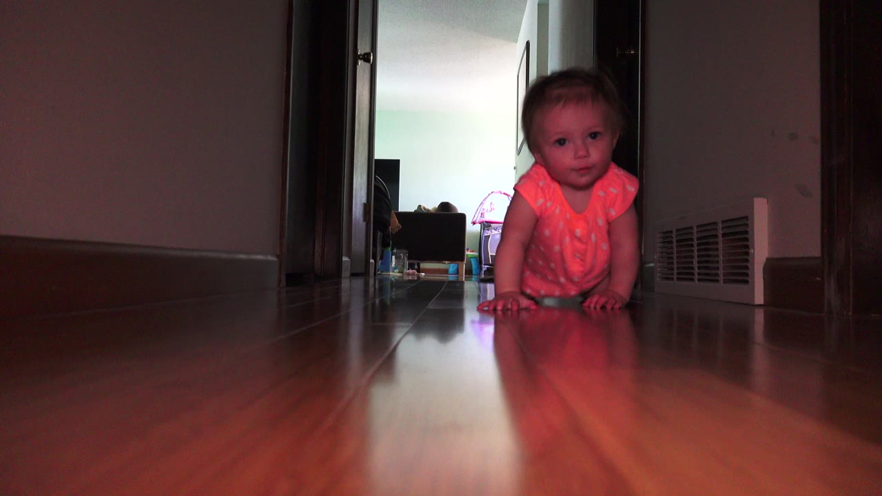 Blond baby crawling at the far end of a dark hallway.