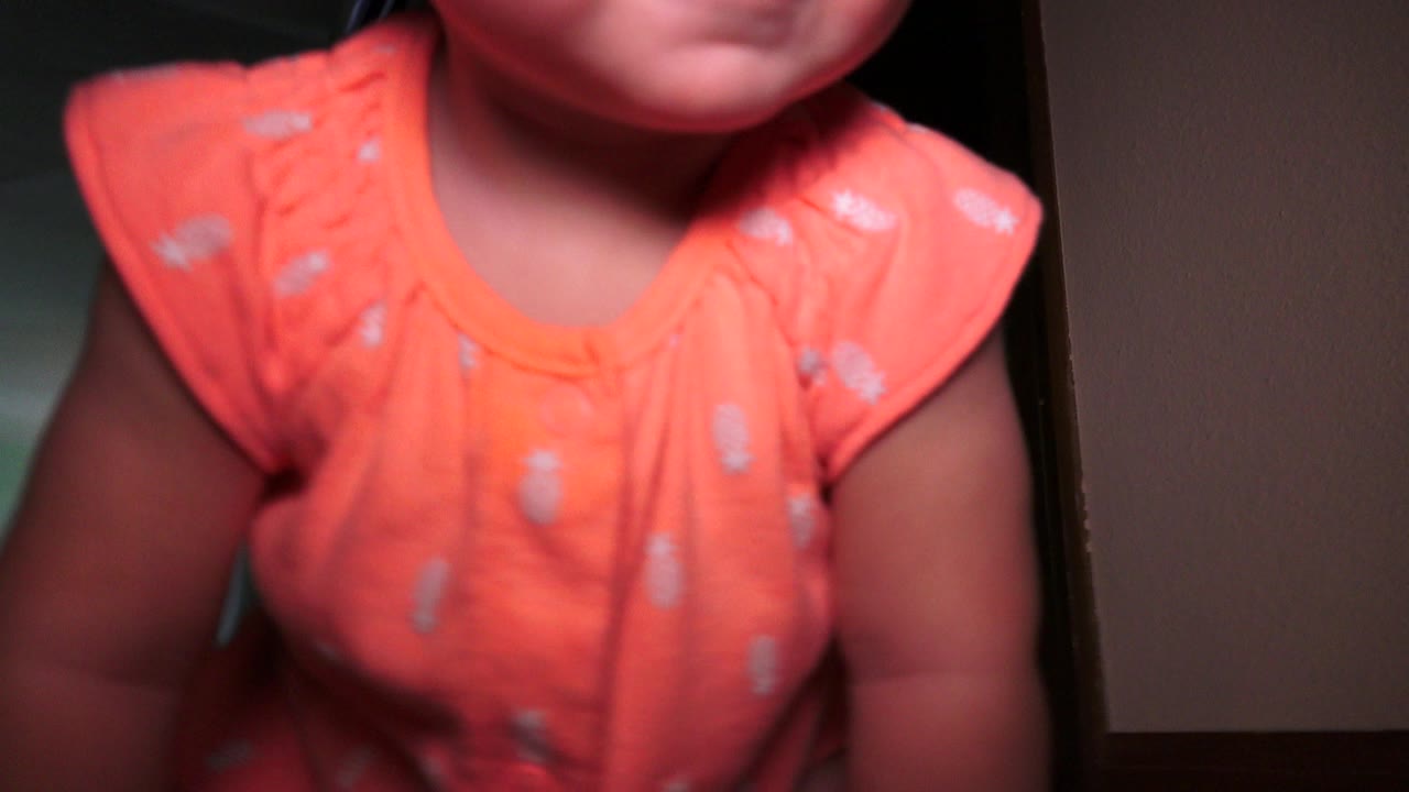 Close cropped toddler in an orange shirt near a doorway.