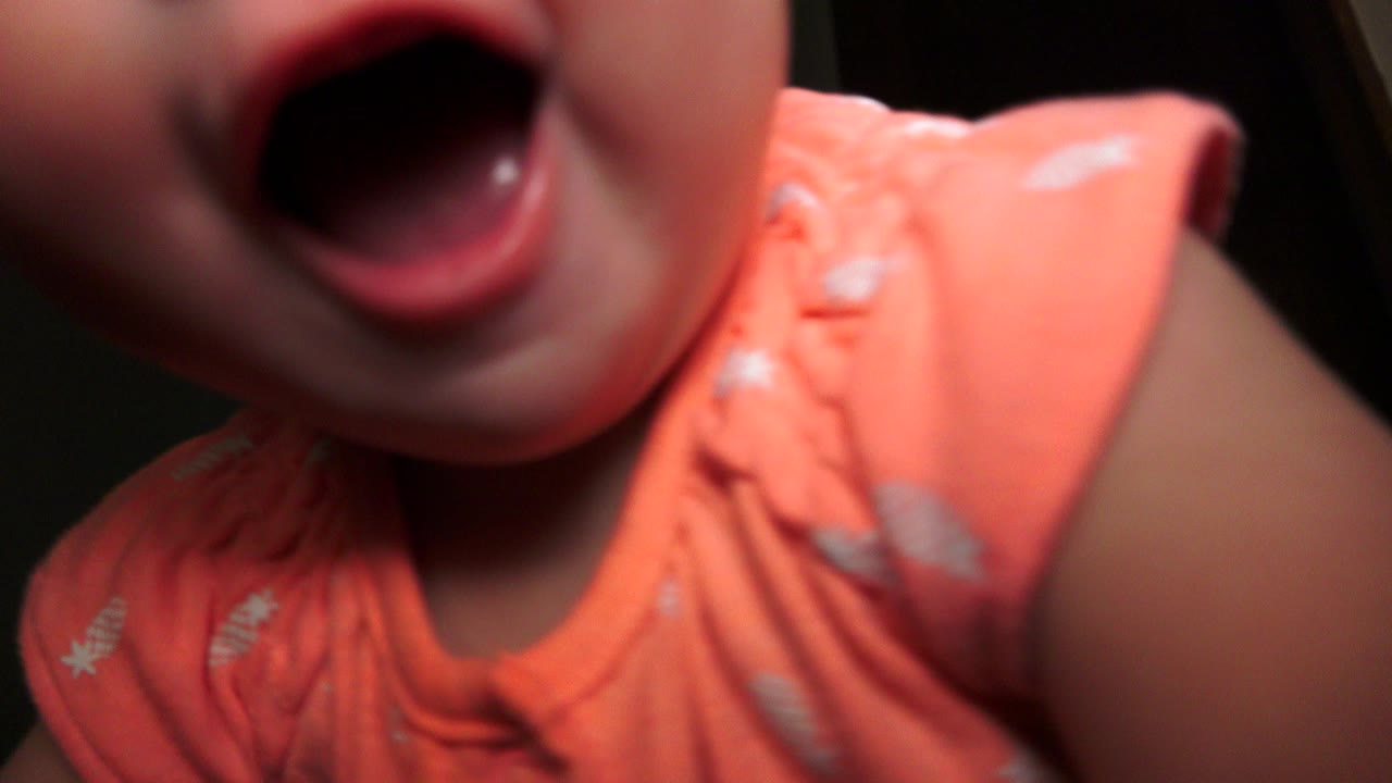 Close baby mouth and orange shirt near the camera.