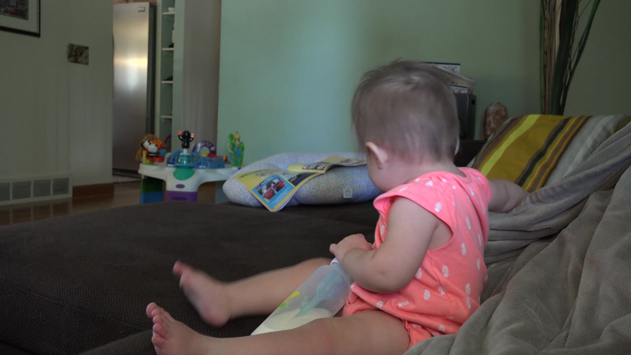 Baby turned away on the couch with one leg lifted.
