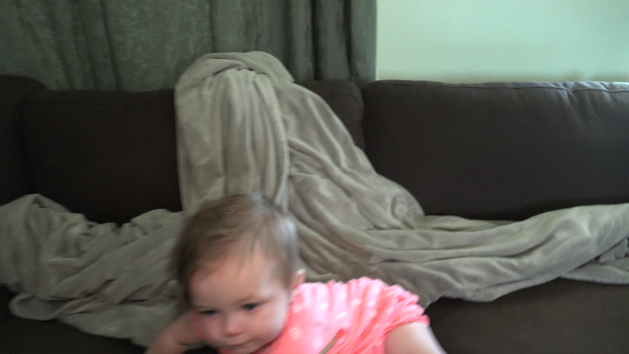In Broomfield, Colorado, the baby remains low in frame with the maroon sofa and grey blanket filling most of the background.