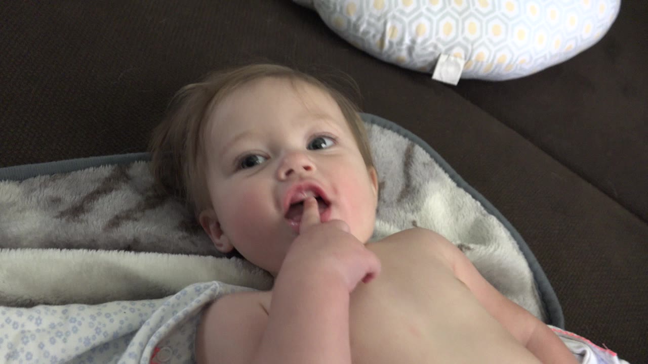 Baby lying on a blanket with a finger in mouth