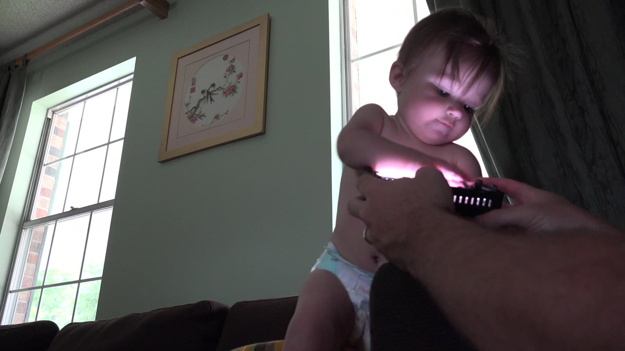 Toddler in a diaper kneeling on a couch near bright windows