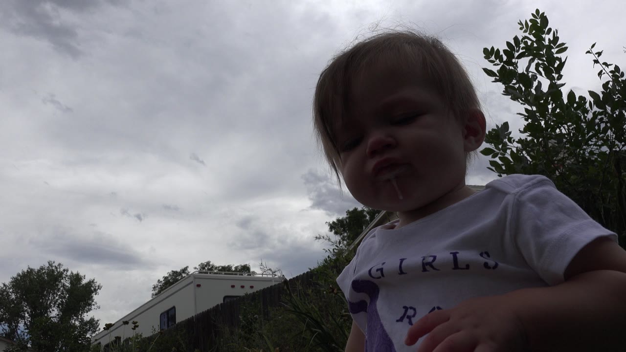 Baby close to a low camera under a cloudy sky.