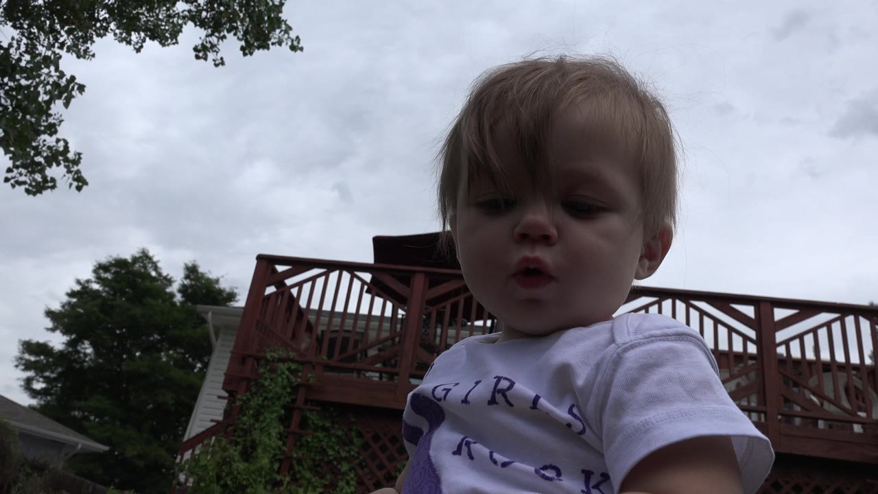 Blonde child close to the camera under a cloudy sky.