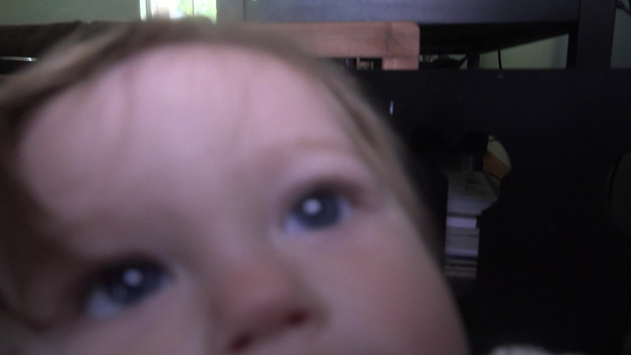 Blurred close-up of a child's face near a low camera in a living room.
