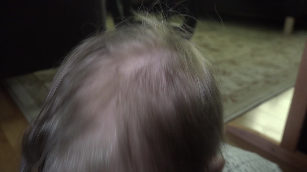Close view of a child's hair near a carpeted floor.