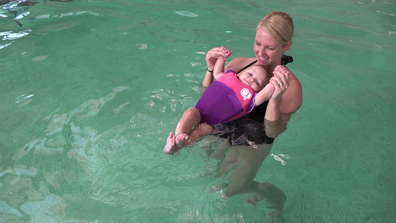 Woman holding a baby floating in a pool.