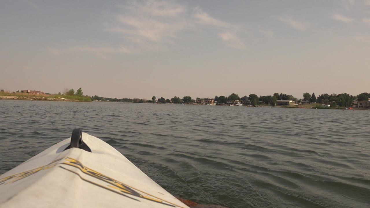 Kayak bow angled toward open lake with far shoreline and trees.