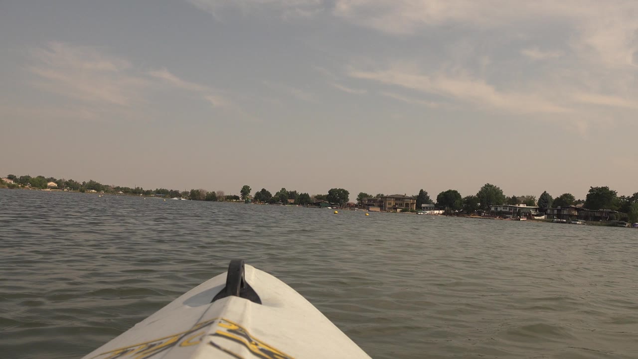 Kayak bow on rippled lake water with distant shoreline.