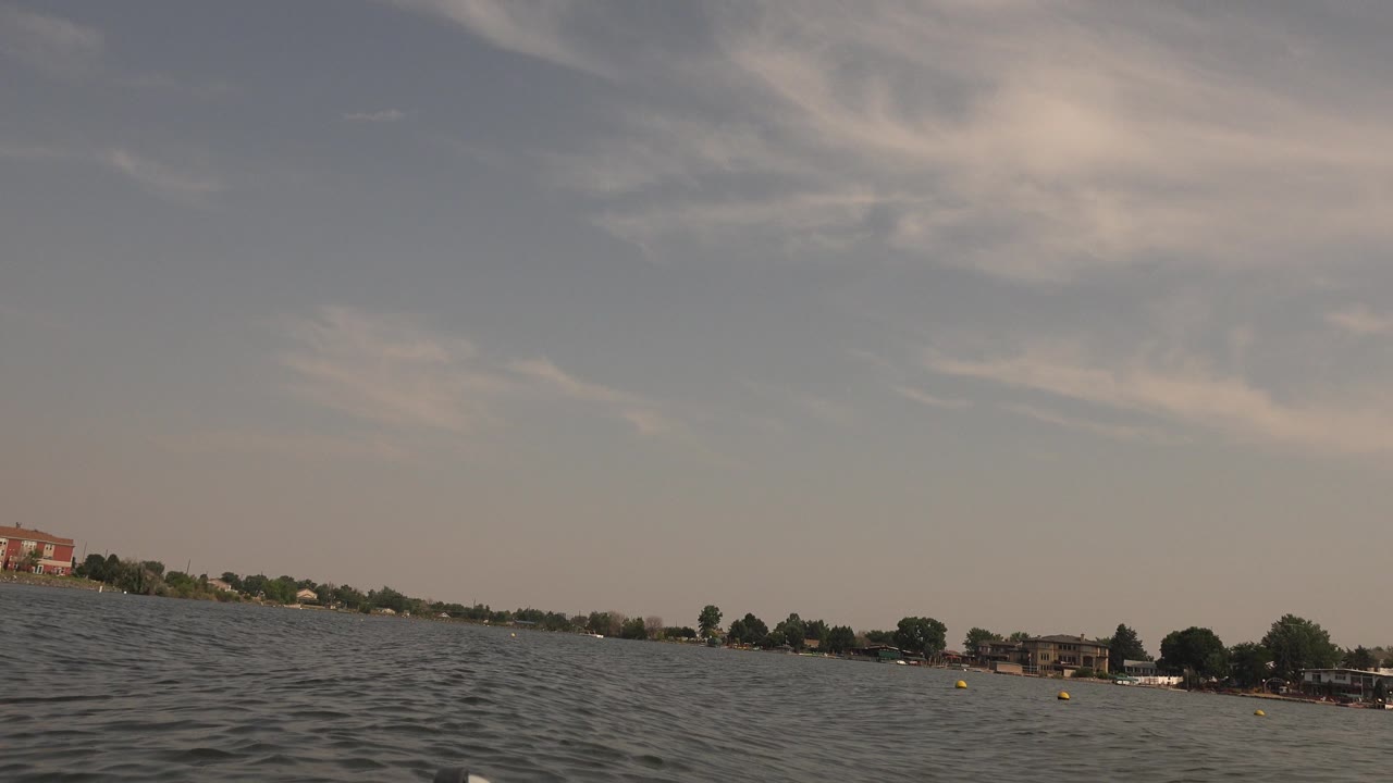 Hidden Lake, Colorado, seen from near the water with small waves, a broad sky, a low shoreline of trees and buildings, and no visible people.