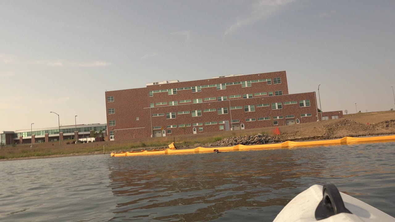 Brick lakeside building, shoreline barrier, and part of a white object at lower right.