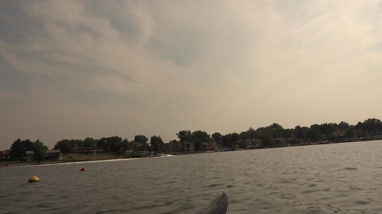 Canoe bow on choppy lake water with distant tree-lined shore
