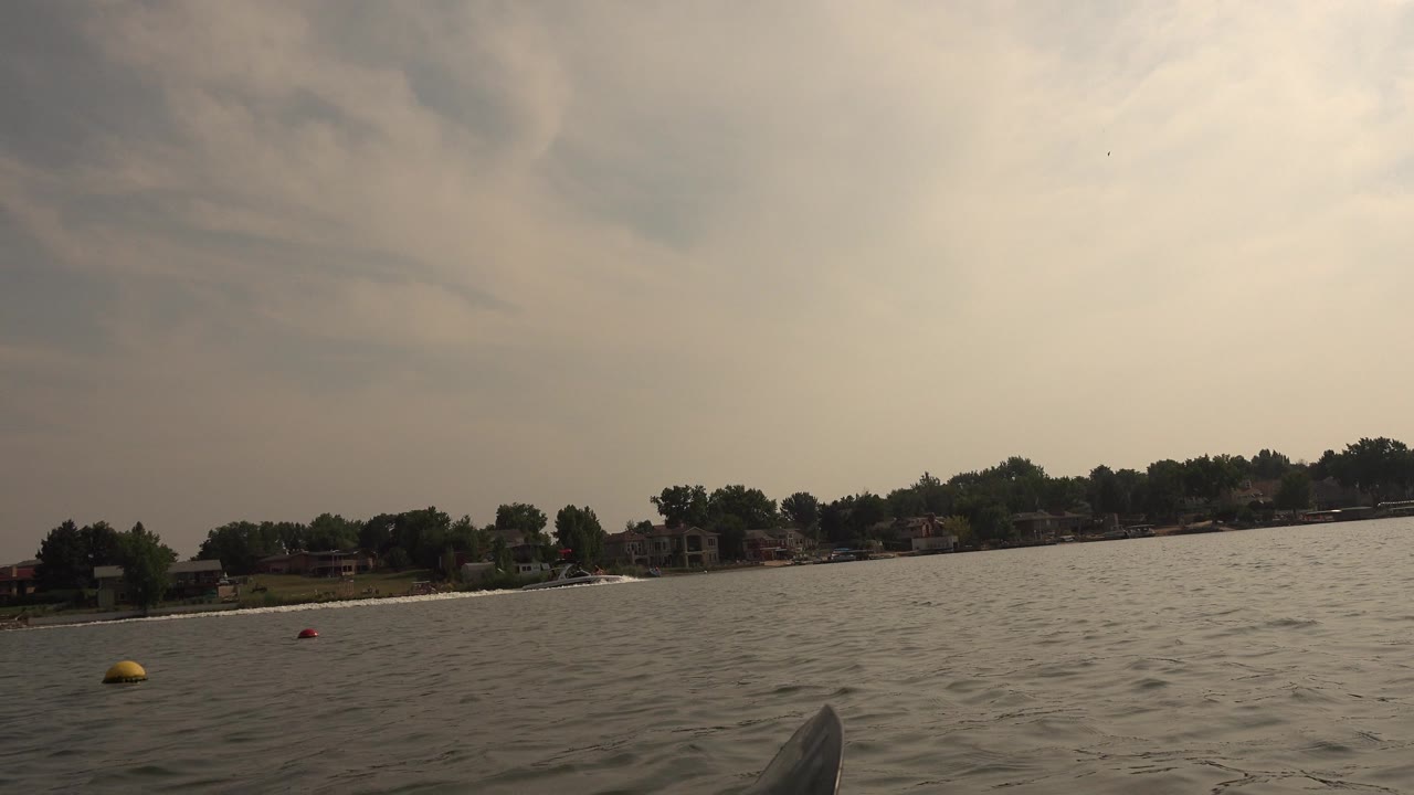 Hidden Lake, Colorado water view with small waves, a yellow buoy left of center, shoreline homes beyond the trees, and no visible people.