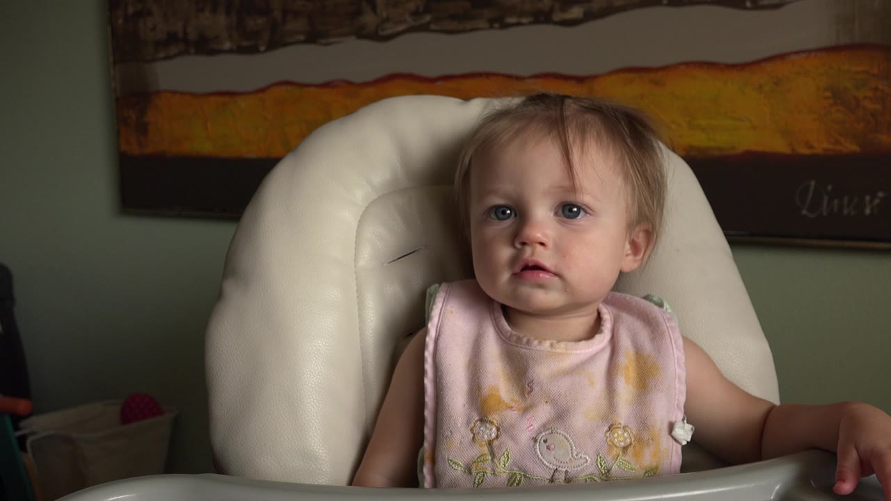 At 0:00 in the Hidden Lake, Colorado clip, a baby in a pale pink bib sits upright in a white high chair with wall art behind them.