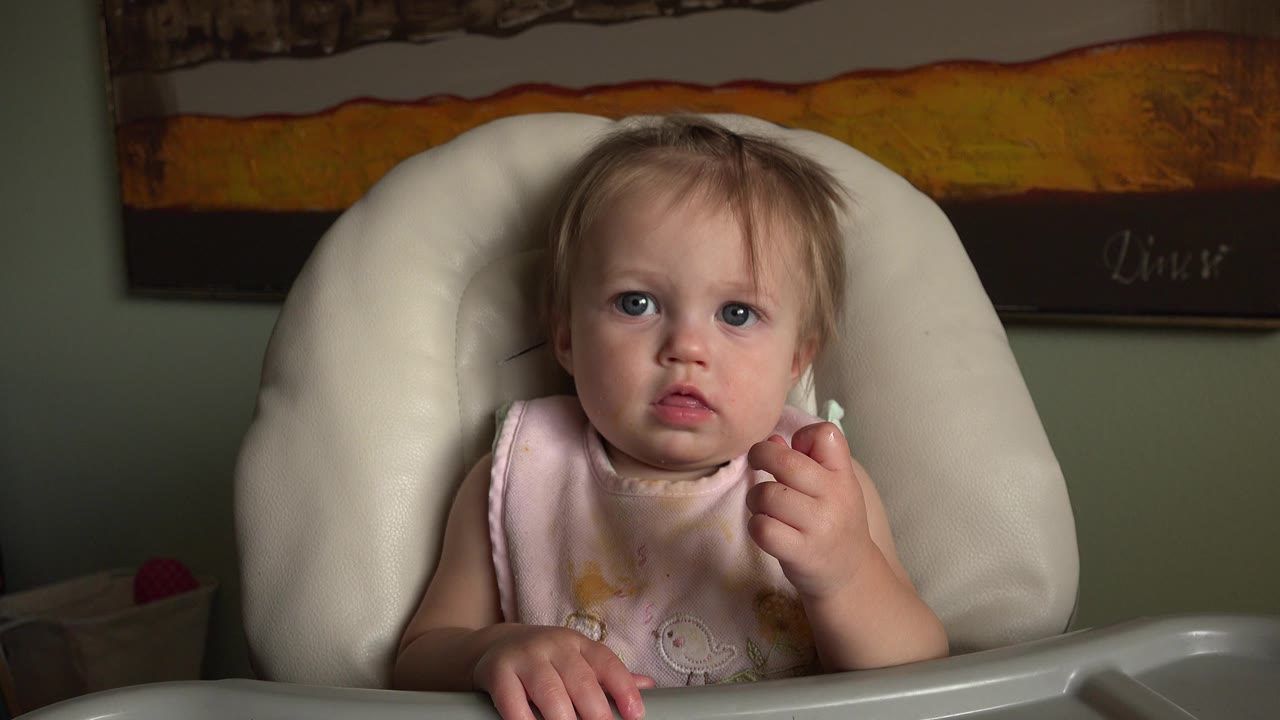 Baby seated in a white high chair indoors.