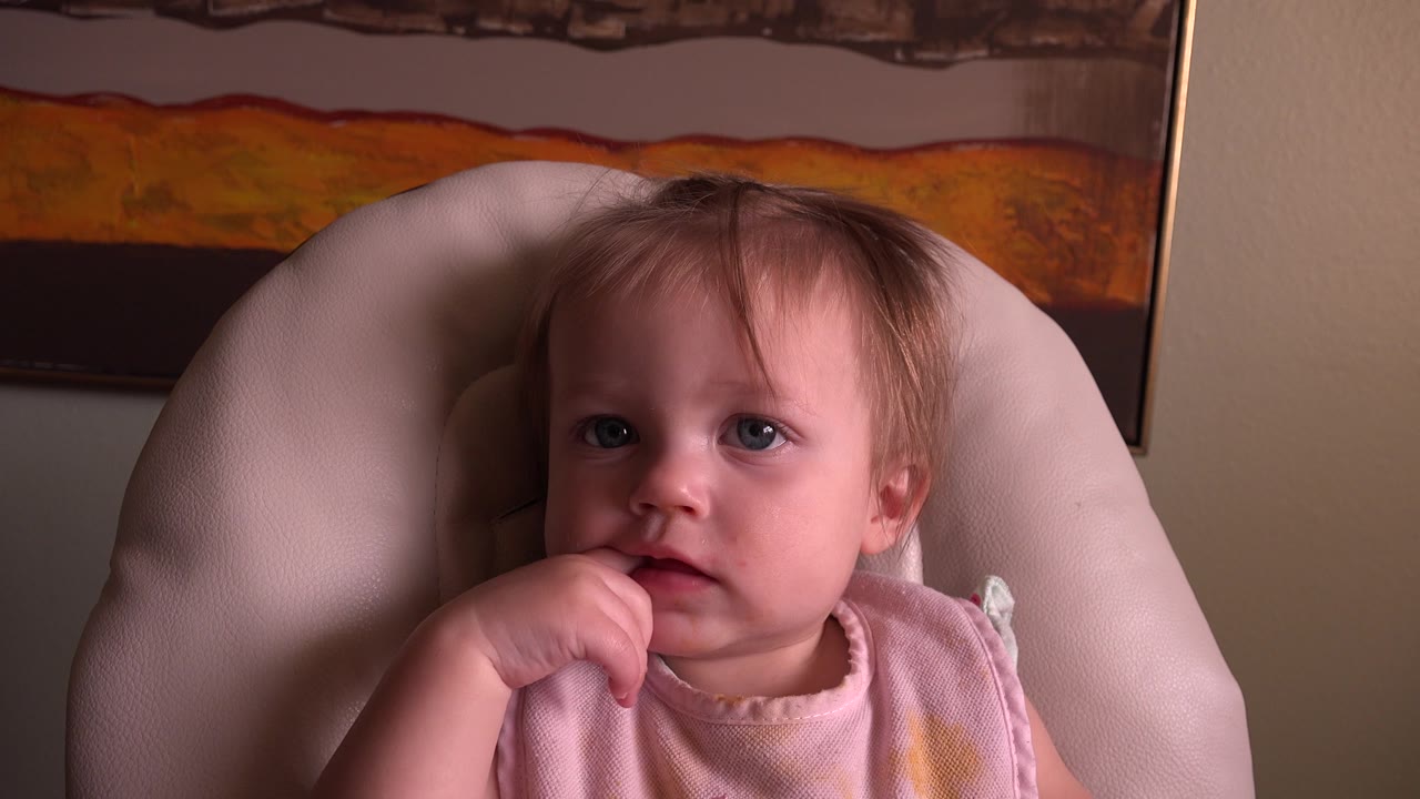 Baby in highchair glancing slightly to the side.