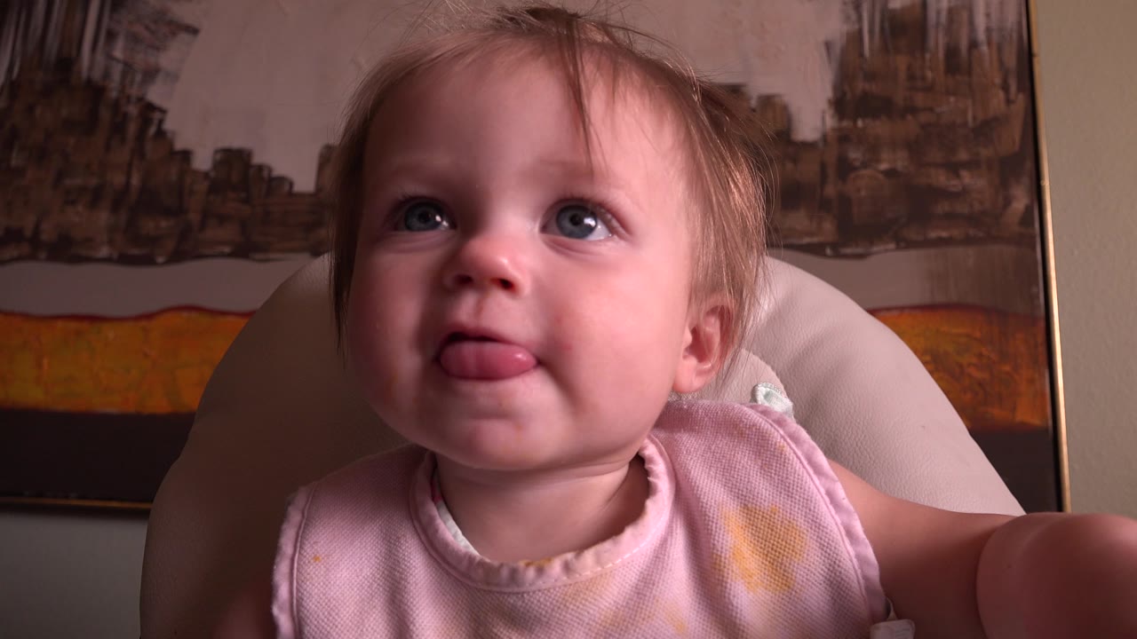 Baby facing the camera with tongue out and wide eyes.