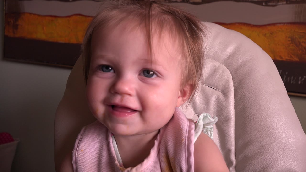 Baby facing forward with a small open-mouth smile.