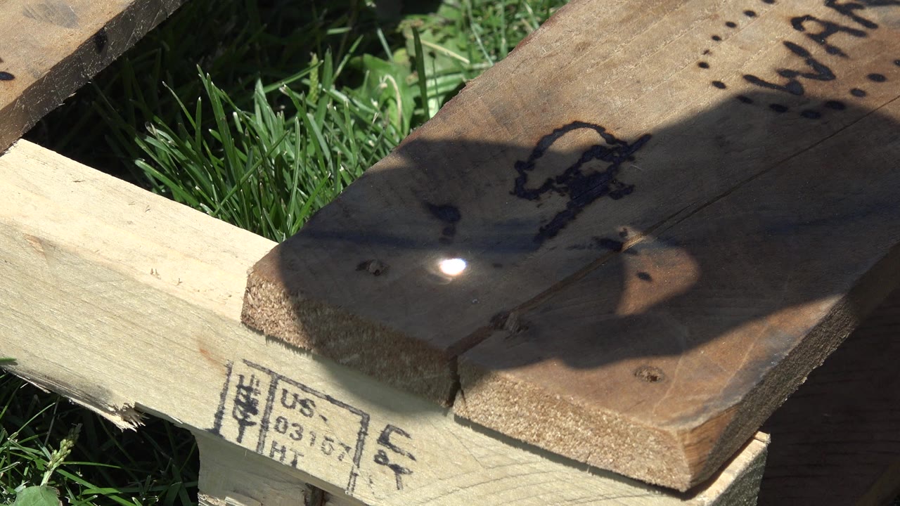 Bright sunlight spot on marked wooden boards over grass