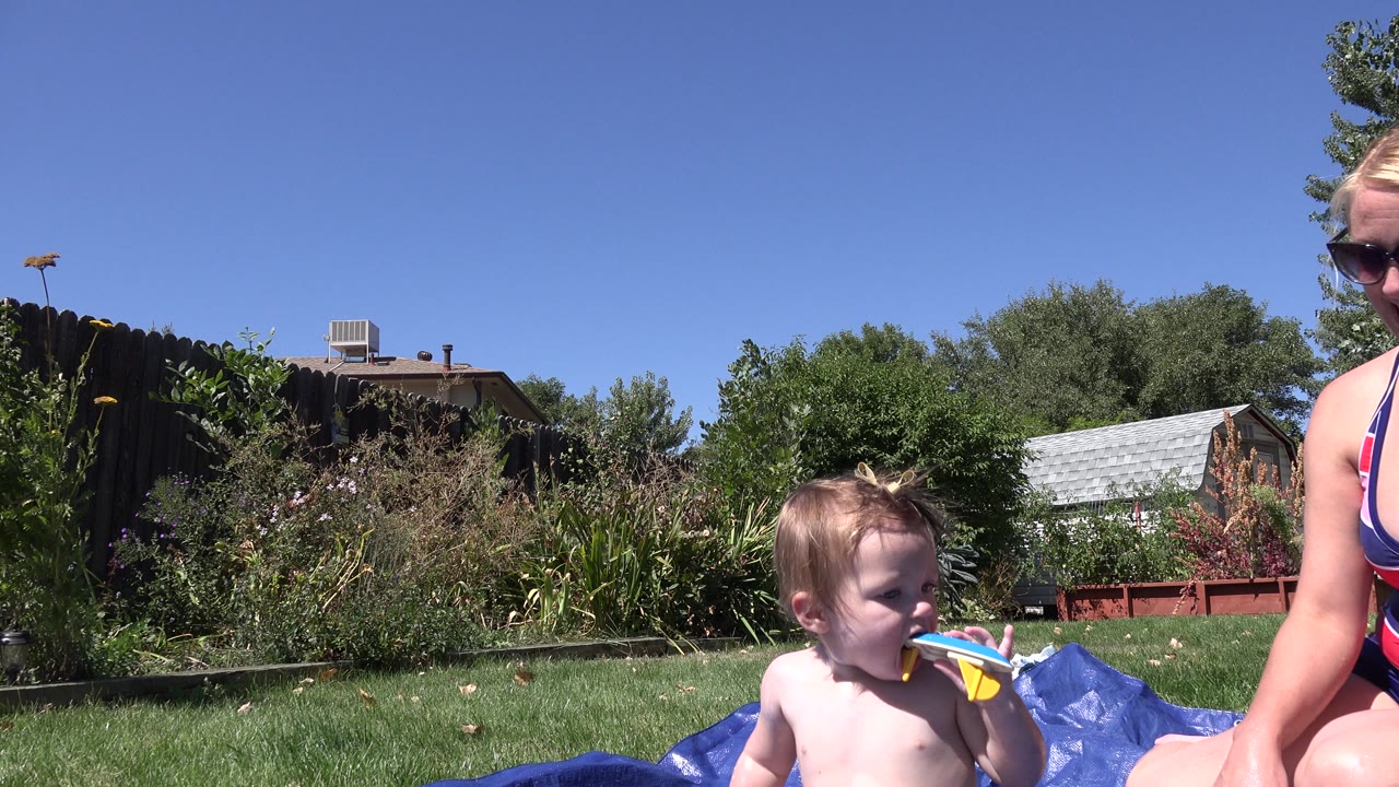 Child seated by blue pool material with a woman cropped at the side of the frame.