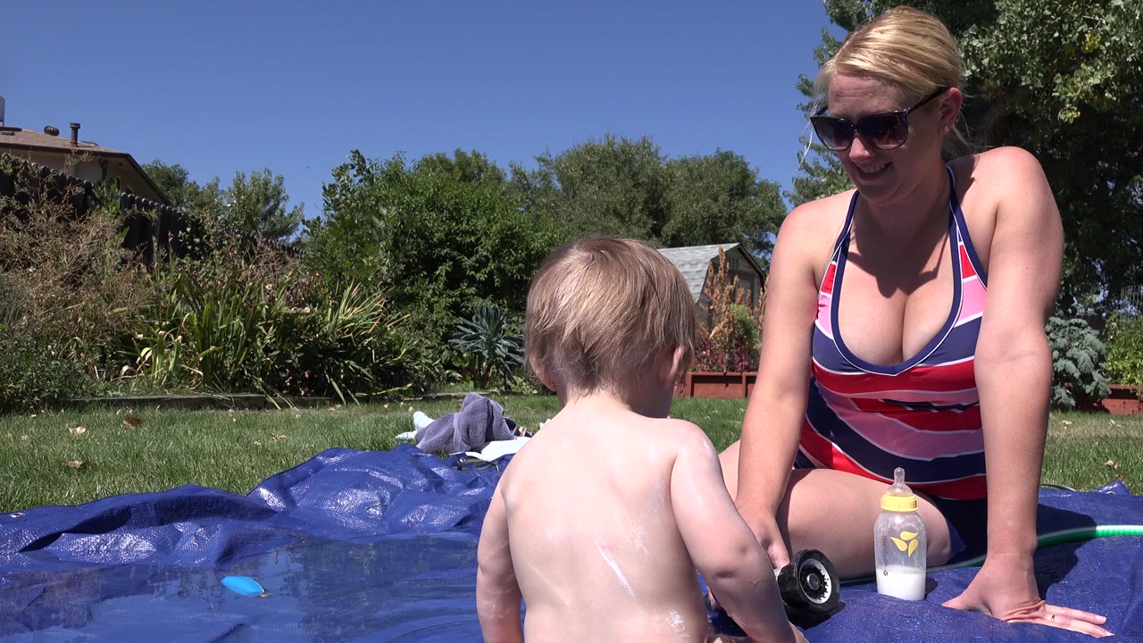 Woman and young child beside a blue backyard pool tarp.