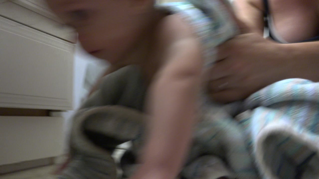 In Westminster, Colorado, the baby and towel remain close to the lens while the woman's arms steady the child beside a pale bathroom cabinet.