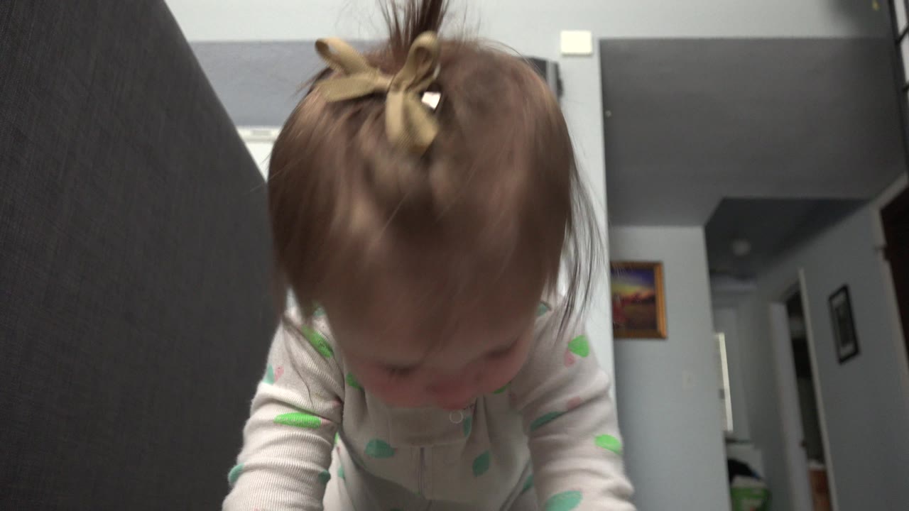 Toddler leaning forward close to a low camera inside a home.