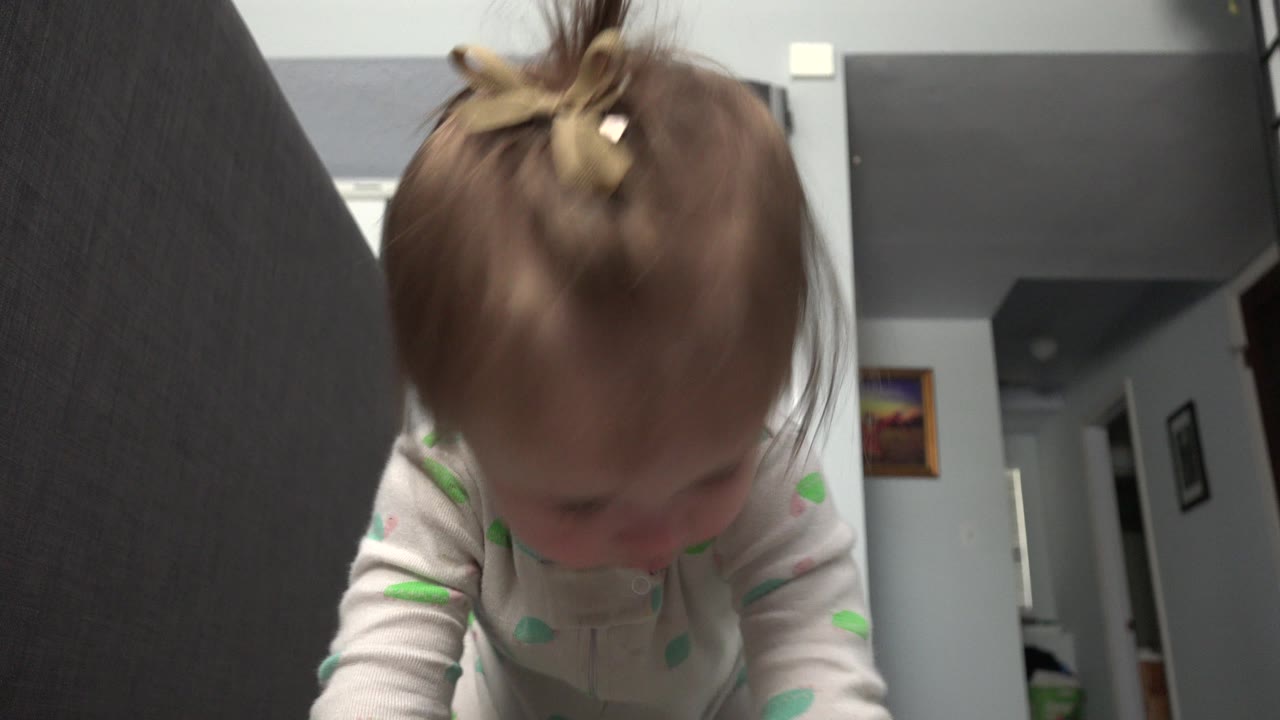 At 0:01, the toddler in Westminster, Colorado stays low and forward-facing, with hair and shoulders prominent and the room's hallway visible behind.