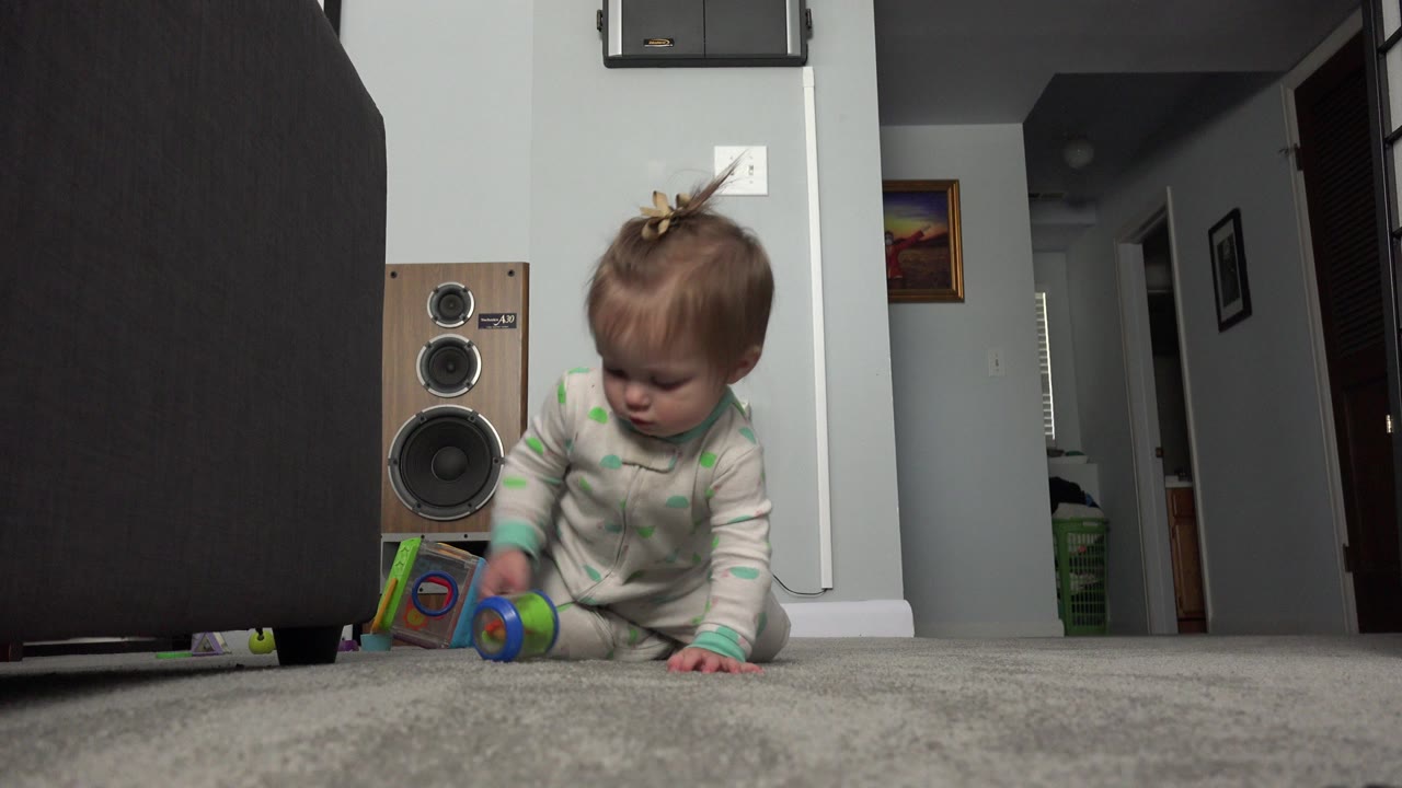 Baby sitting on carpet beside a colorful toy in a home interior.