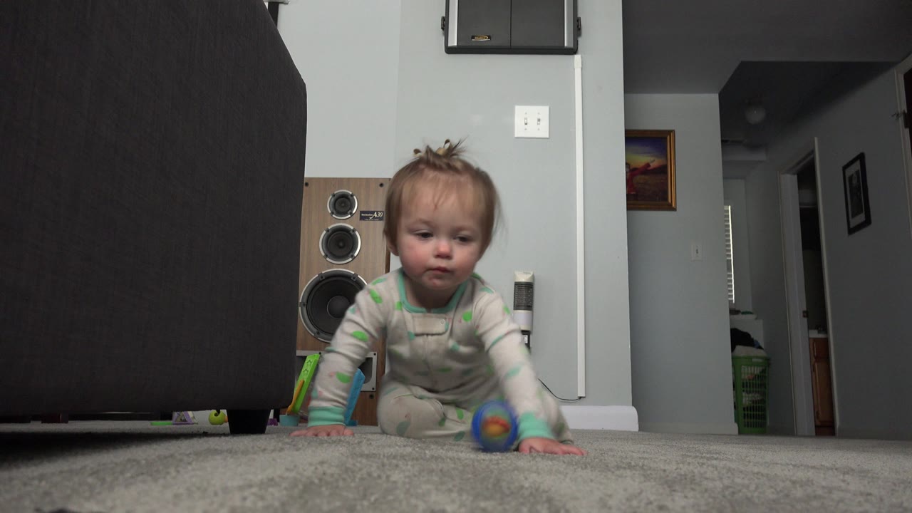 Blonde child crawls on carpet toward a low camera.