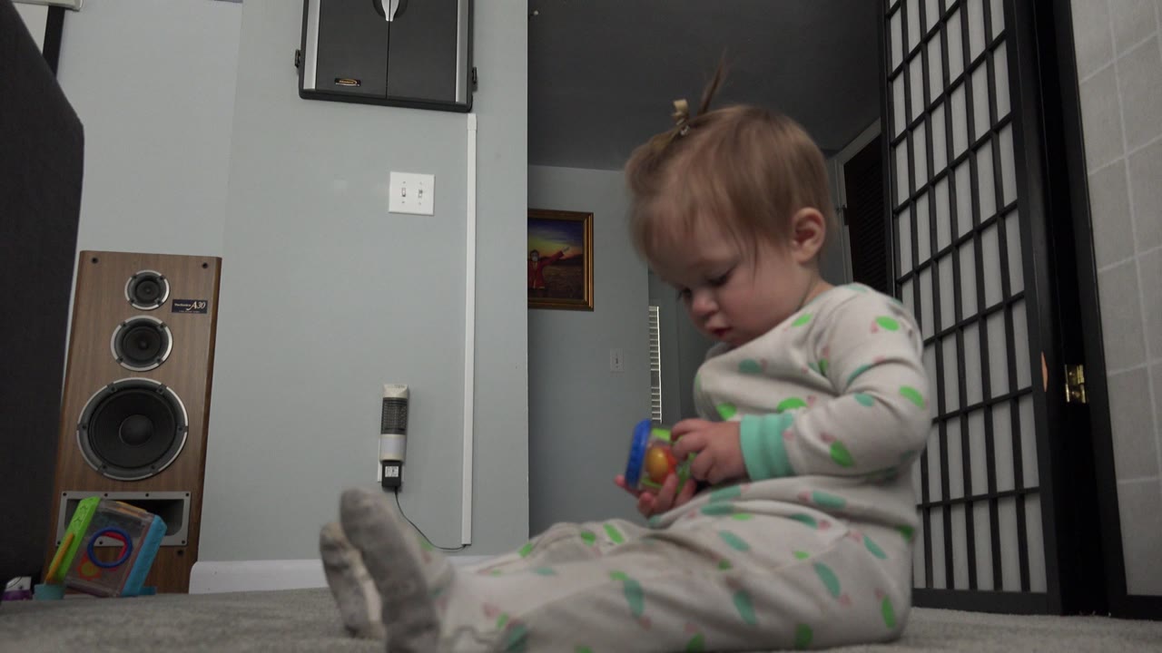 Toddler sitting on carpet with a toy in a home interior.
