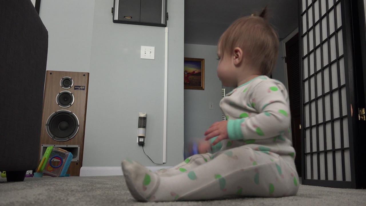 Baby sits near a black room divider, facing toward the doorway.