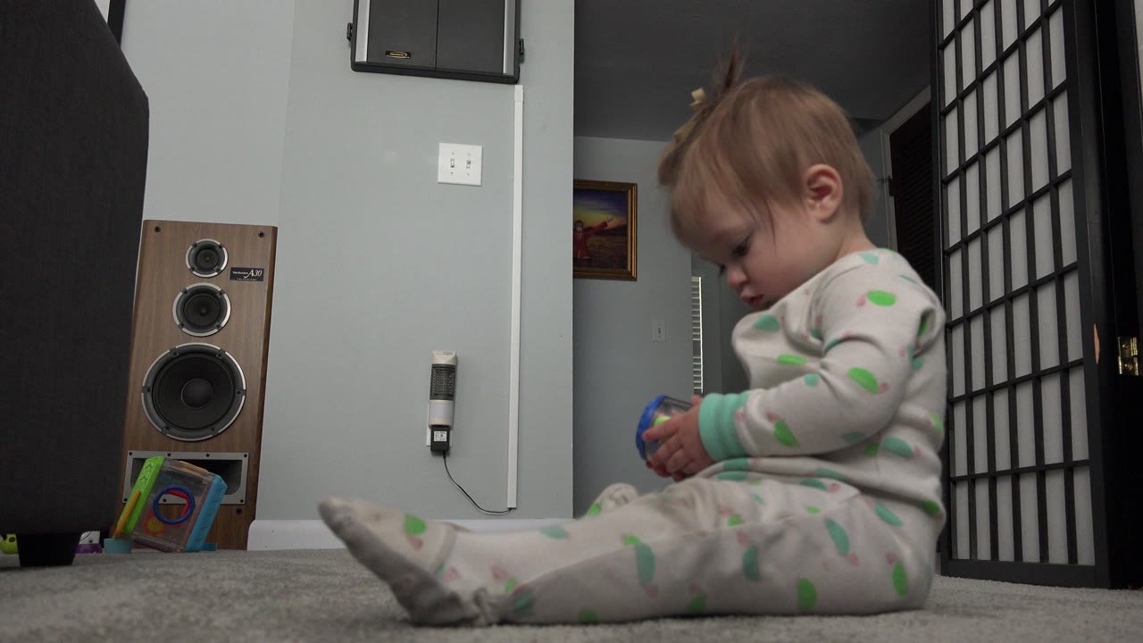 Young child sitting on carpet and looking down at a toy.