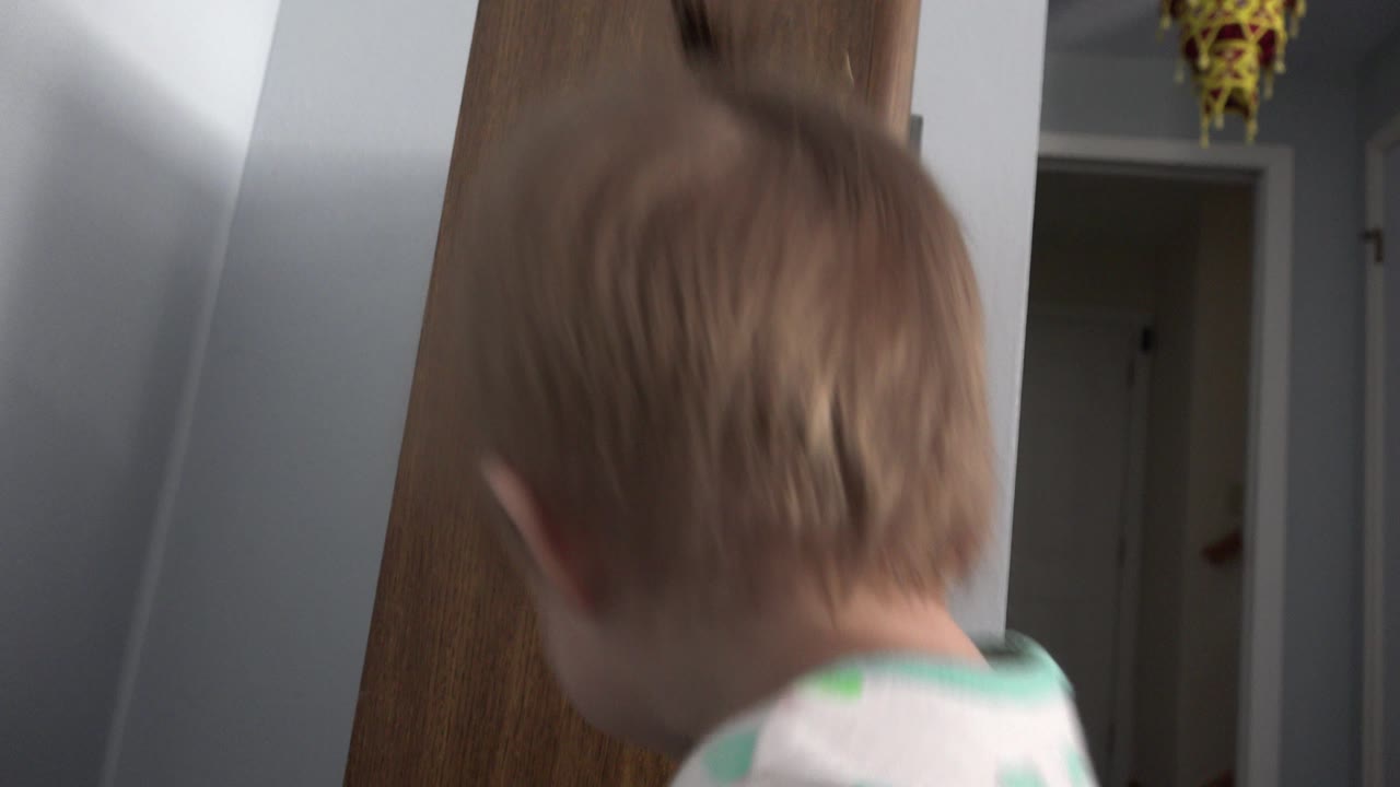 Toddler close to a wood speaker in a home interior.