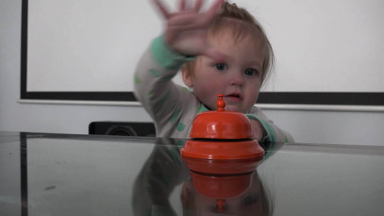 Toddler reaches upward with a blurred arm near the table.
