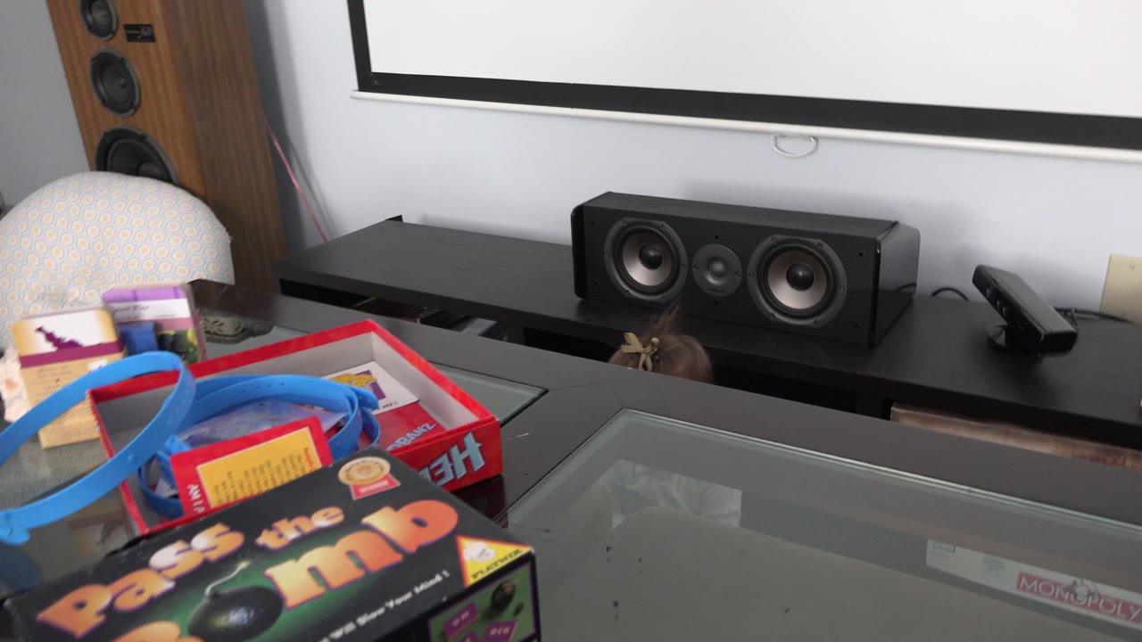 At 0:01 in Westminster, Colorado, the tabletop games and blue track remain in the foreground as the baby stays partly hidden near the speaker shelf and projector screen.